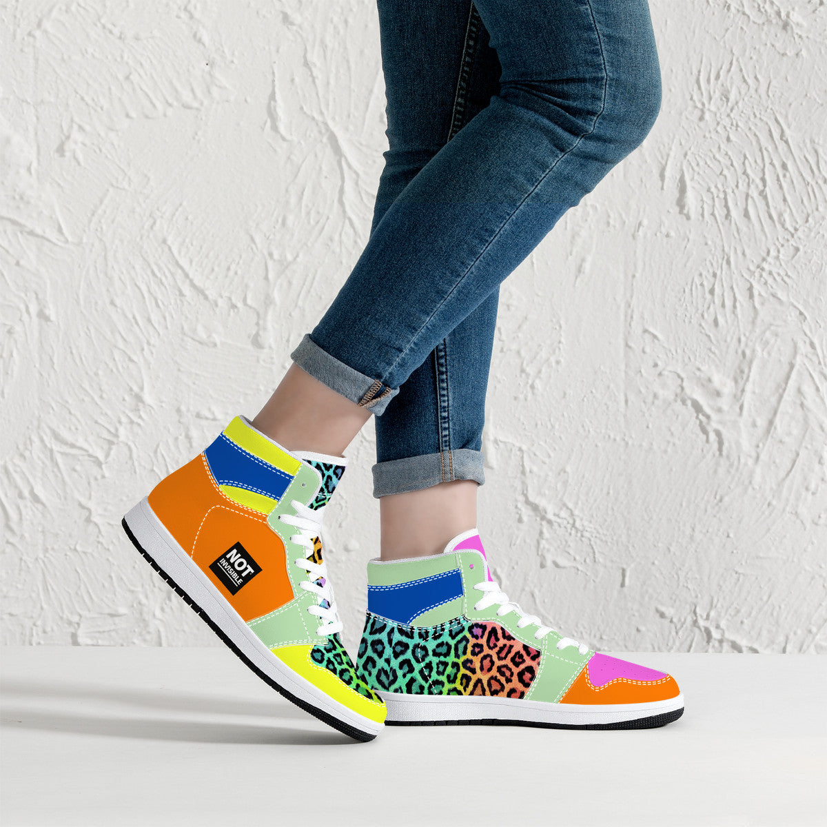 Colorful patterned sneakers worn with blue jeans against a white background