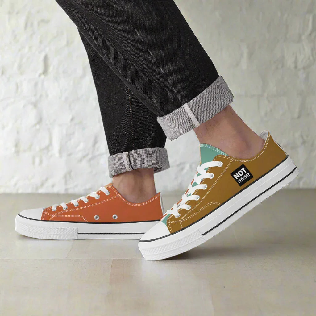 Two pairs of sneakers, one orange and one brown, worn by a person with rolled-up jeans.