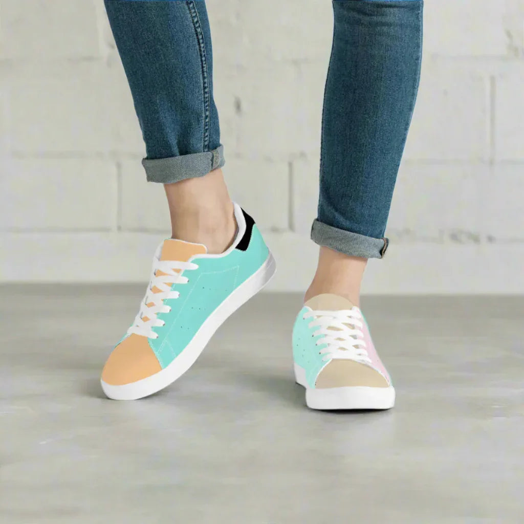 Teal and beige sneakers worn with rolled-up jeans on a neutral background