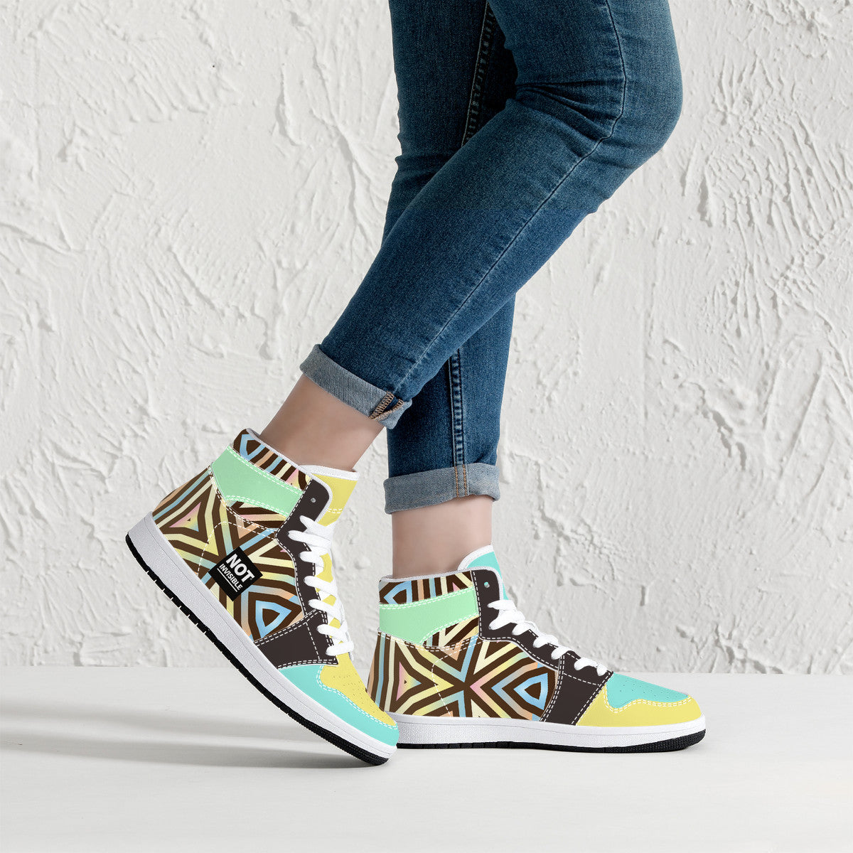 Colorful patterned sneakers worn with blue jeans against a white background